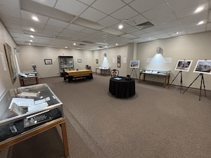 Photograph of a the exhibit room with exhibit cases and wall hangings from the collection.