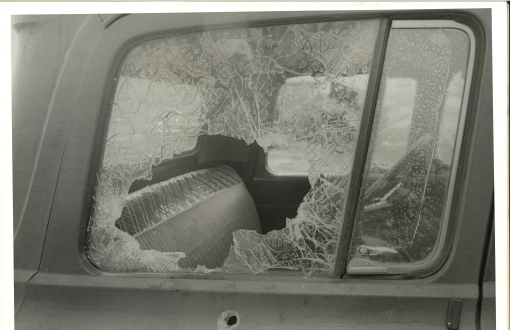 Image of a truck window that has been shattered. A bullet hole is below the window showing that the truck had been shot at.